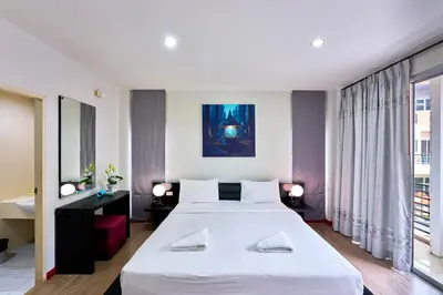 a bedroom with a large white bed and a large window at Jinta Andaman in Kata Beach