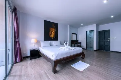 a bedroom with a bed with a painting on the wall at Jinta Andaman in Kata Beach