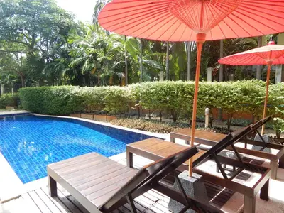 two chairs and an umbrella next to a swimming pool at Jinta Andaman in Kata Beach