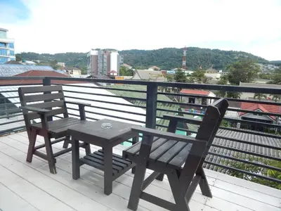 a wooden table and two chairs on a balcony at Jinta Andaman in Kata Beach