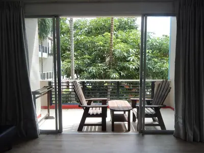 a room with two chairs and a table on a balcony at Jinta Andaman in Kata Beach