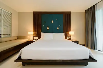 a bedroom with a large white bed with a blue headboard at Centara Anda Dhevi Resort & Spa Krabi in Ao Nang Beach