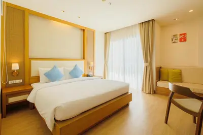 a bedroom with a large white bed with blue pillows at ASHLEE Plaza Patong Hotel & Spa in Patong Beach