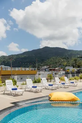 a swimming pool with lounge chairs and a mountain at ASHLEE Plaza Patong Hotel & Spa in Patong Beach