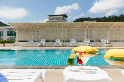 two glasses of wine on tables next to a swimming pool at ASHLEE Plaza Patong Hotel & Spa in Patong Beach