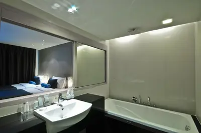 a bathroom with a sink and a tub and a mirror at ASHLEE Heights Hotel Patong in Patong Beach