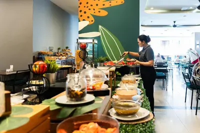 a woman standing in a kitchen preparing food at Gu Hotel Patong in Patong Beach