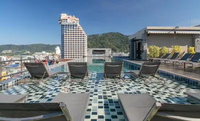 a pool on the roof of a building with chairs at Gu Hotel Patong in Patong Beach