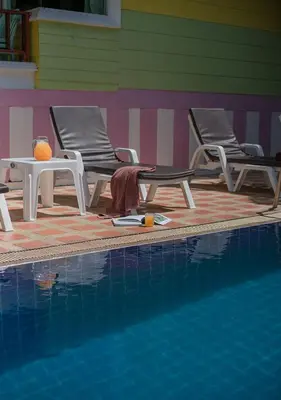 two chairs and a table next to a swimming pool at Lemon House in Patong Beach