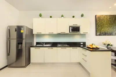 a kitchen with white cabinets and a stainless steel refrigerator at Villa Hahana Private Pool Near Nai Harn Beach in Rawai Beach