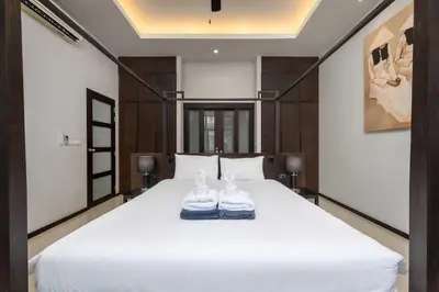 a bedroom with a white bed with two shoes on it at VILLA Iotama Private Pool Nai Harn Beach in Rawai Beach