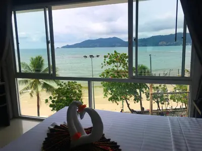 two swans sitting on a bed in front of a window at The Front Hotel and Apartments in Patong Beach