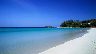 a person standing on a beach in the ocean at Ozone Condotel Kata Beach by PHR in Kata Beach