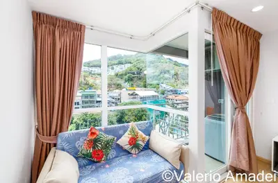 a living room with a blue couch and a large window at Ozone Condotel Kata Beach by PHR in Kata Beach