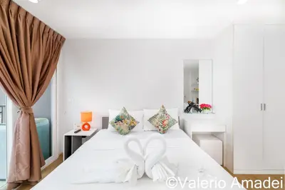 a bedroom with a white bed with a bow on it at Ozone Condotel Kata Beach by PHR in Kata Beach