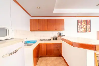 a small kitchen with wooden cabinets and a sink at Sai Rougn Residence - SHA Extra Plus in Patong Beach