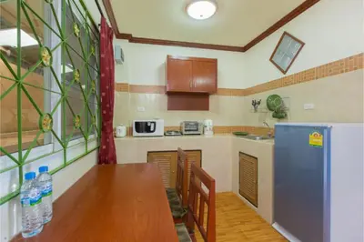 a kitchen with a wooden table and a refrigerator at Patong Rai Rom Yen Resort SHA in Patong Beach