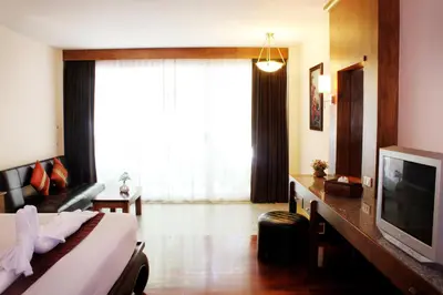a hotel room with a bed and a television at Baan Pron Phateep in Patong Beach
