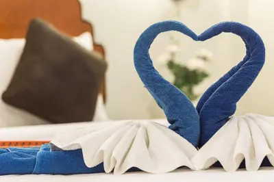 a blue and white towel with two hearts on a bed at Kasemsuk Hotel Karon in Karon Beach