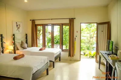 a hotel room with two beds and a television at Phuket Muay Thai House in Chalong