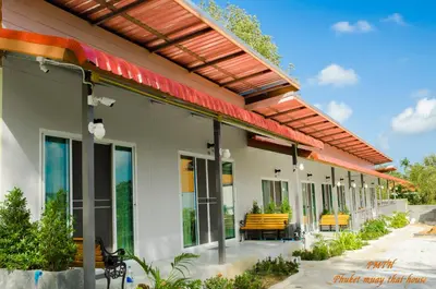 an outdoor patio with yellow benches and a pergola at Phuket Muay Thai House in Chalong