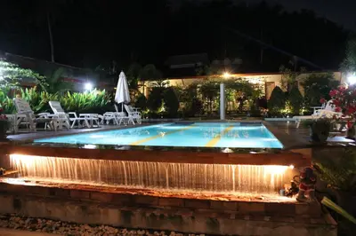 a swimming pool at night with a water fountain at Phuket Muay Thai House in Chalong