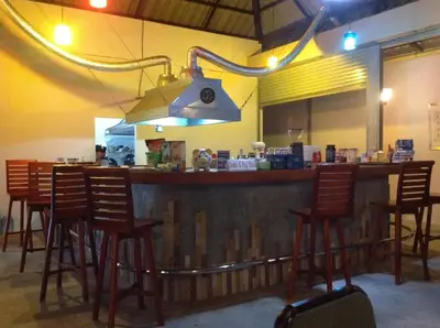 a bar with a row of wooden bar stools at Phuket Muay Thai House in Chalong