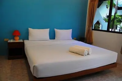 a large white bed with a towel on it at Hacienda Phuket, Patong in Patong Beach