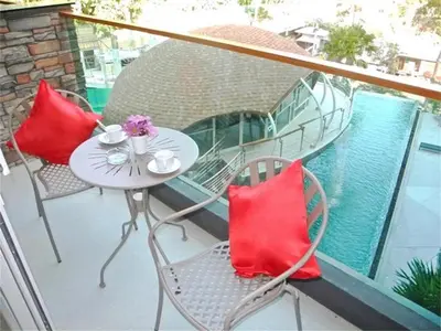 a balcony with chairs and a table with red pillows at Emerald Terrace Patong in Patong Beach