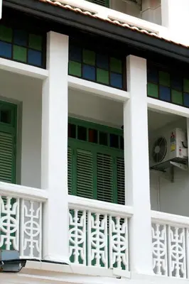 a white house with green and colorful windows at 99 Oldtown Boutique Guesthouse SHA EXTRA PLUS in Phuket Town