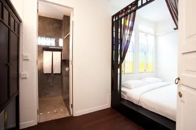 a bedroom with a bed and a glass door leading to a shower at 99 Oldtown Boutique Guesthouse SHA EXTRA PLUS in Phuket Town