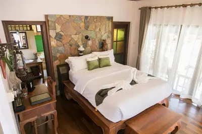 a bedroom with two beds and a stone wall at West Key Kamala Villa in Kamala Beach