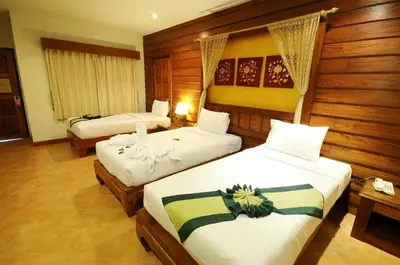 two beds in a room with wooden walls at Bel Aire Patong in Patong Beach