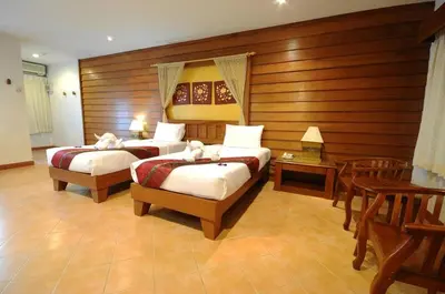 two beds in a room with wooden walls at Bel Aire Patong in Patong Beach