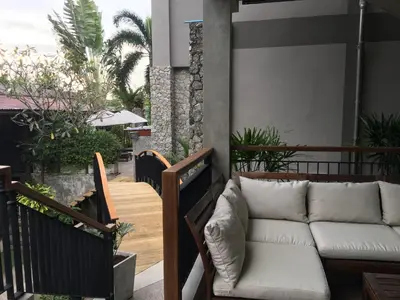 a couch on the balcony of a house at Baan Andaman Sea Surf in Patong Beach
