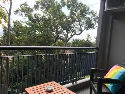 a balcony with a table and a tree at Baan Andaman Sea Surf in Patong Beach