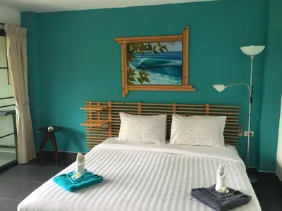 a bedroom with a large bed with a blue wall at Baan Andaman Sea Surf in Patong Beach