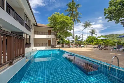 a swimming pool next to a building with a resort at Patong Lodge Hotel - Thailand's Green Hotel Plus in Patong Beach