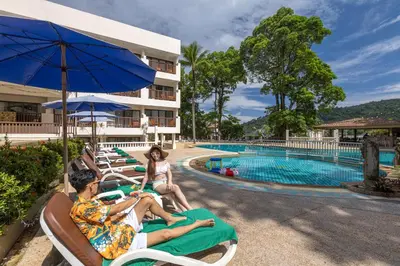 a group of people sitting on lawn chairs by a pool at Patong Lodge Hotel - Thailand's Green Hotel Plus in Patong Beach