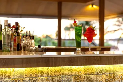 a bar with two cocktails sitting on a counter at Patong Lodge Hotel - Thailand's Green Hotel Plus in Patong Beach