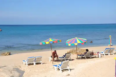 a group of people sitting on a beach with umbrellas at Patong Lodge Hotel - Thailand's Green Hotel Plus in Patong Beach