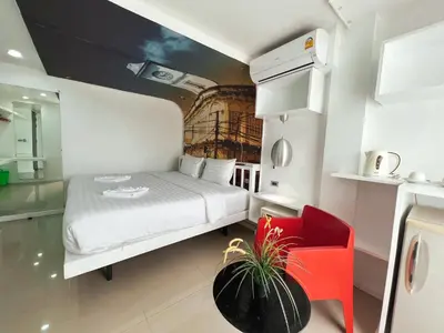 a small bedroom with a white bed and a red chair at The Color Kata in Kata Beach