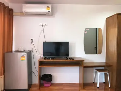a room with a desk with a television and a refrigerator at Boodsarin Hotel in Ko Yao Yai