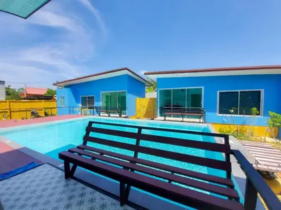 a swimming pool with a bench in front of a house at 2 Home in Chalong