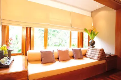 a couch sitting in front of a window with pillows at Nakamanda Resort and Spa in Klong Muang Beach