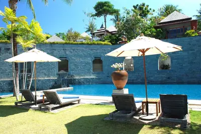 a group of chairs and umbrellas next to a pool at Nakamanda Resort and Spa in Klong Muang Beach