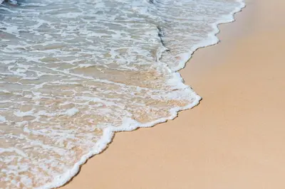 a close up of the ocean waves on the beach at Dang Sea Beach Resort - SHA in Nai Yang Beach
