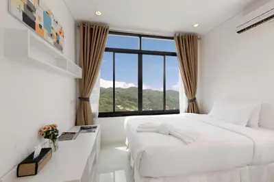 a bedroom with a white bed and a large window at Kamala Regent Residence in Kamala Beach
