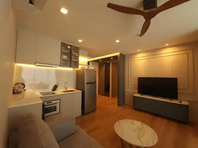 a kitchen and living room with a couch and a tv at The Regent Residence Kamala in Kamala Beach
