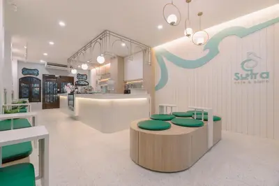 a store with green chairs and a table and a counter at Baan Sutra Guesthouse in Phuket Town